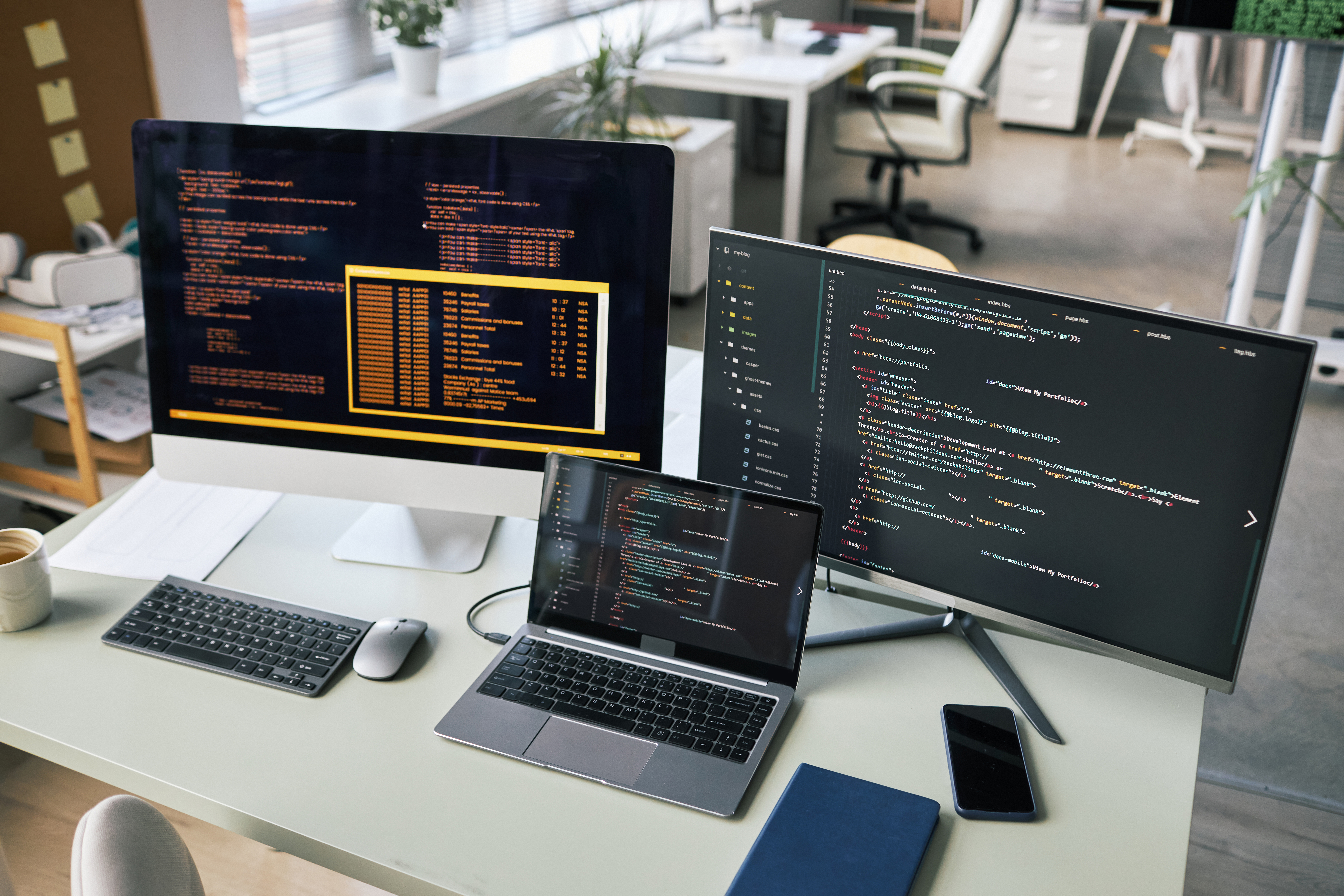 Coding workspace with laptop and screens